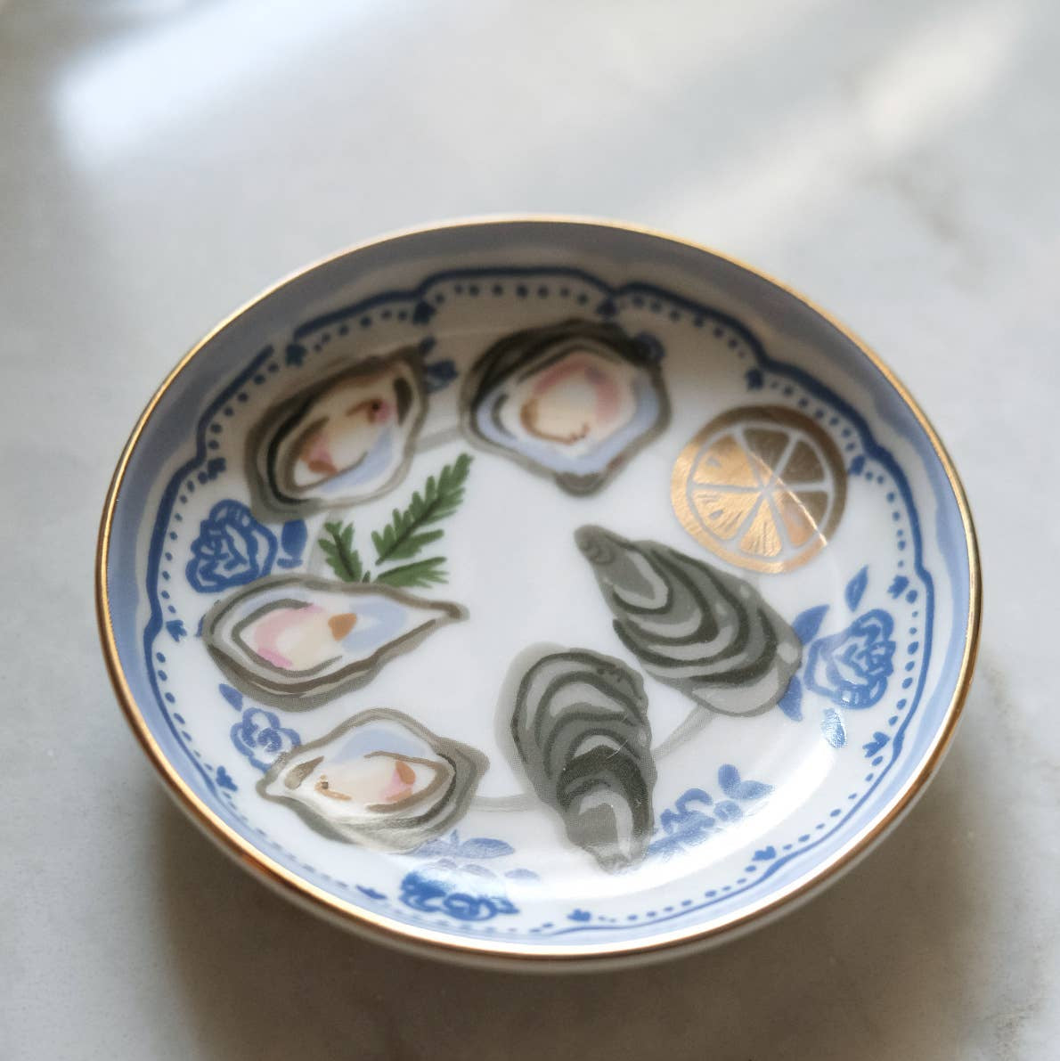 Decorative plate with illustrations of oysters and lemon on a marble surface
