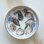 Decorative plate with oyster shells and lemon slices on a white background