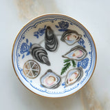 Decorative plate with oyster shells and lemon slices on a white background