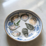 Decorative plate with illustrations of oysters and lemon on a marble surface