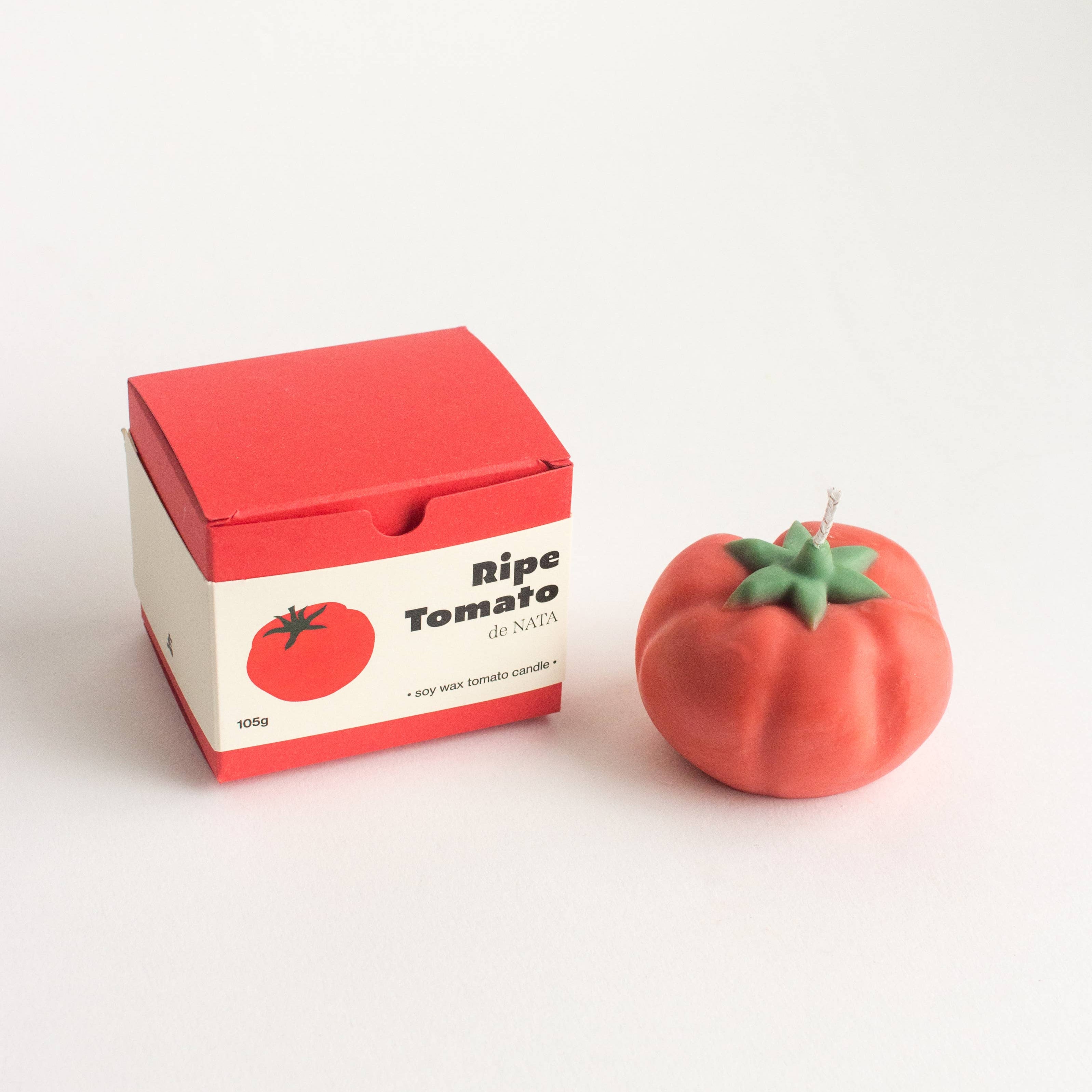 Tomato-shaped candle next to a box labeled 'Ripe Tomato' on a white background