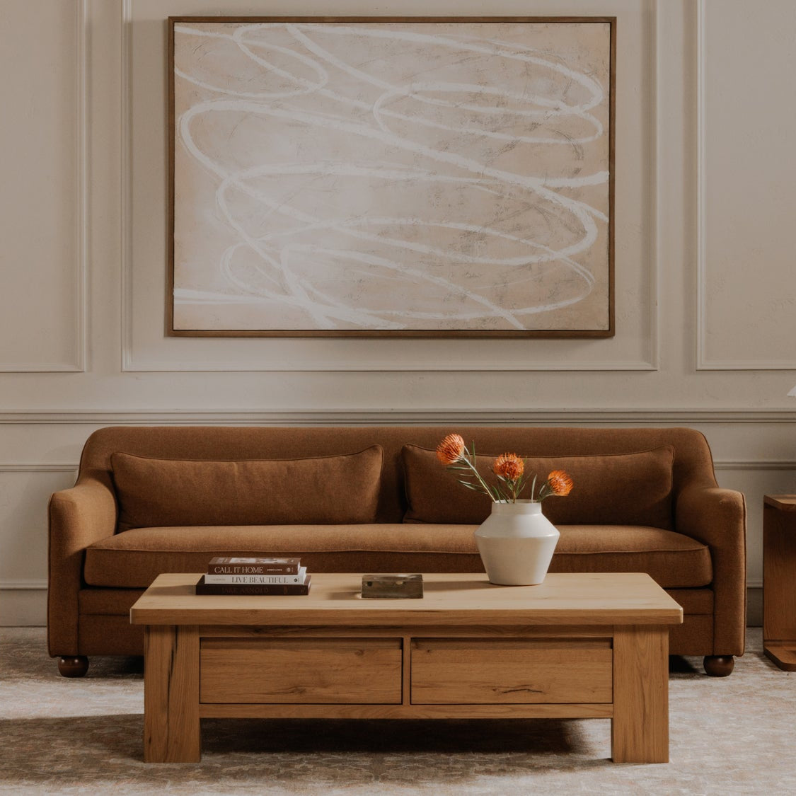 Living room with brown sofa, beige armchair, wooden coffee table, and abstract painting on wall.