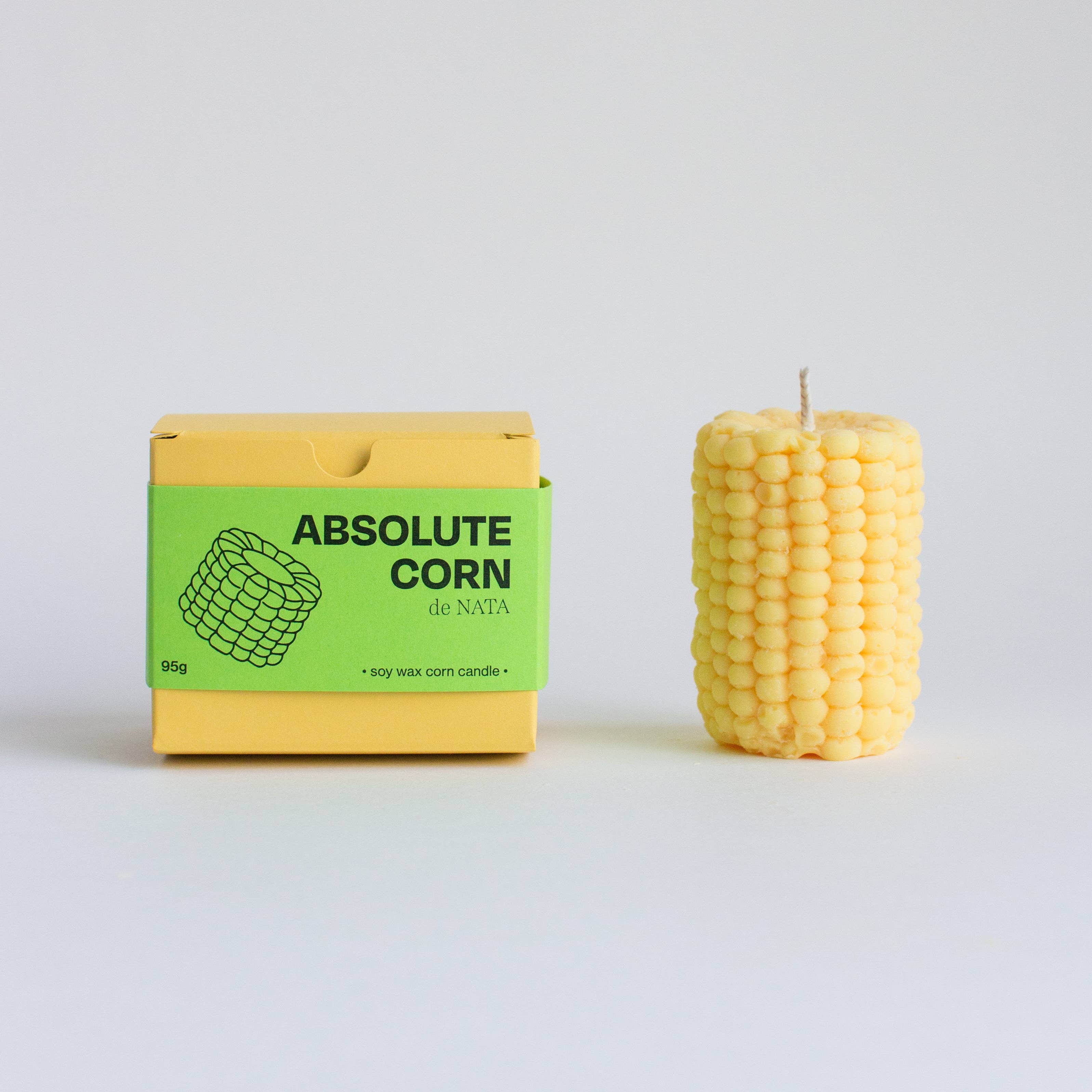Corn-shaped candle next to its packaging on a light gray background