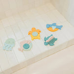 Four colorful animal-shaped bath toys arranged on a white tiled bathtub ledge. The toys include a light blue octopus, a pale pink fish, a yellow turtle, and a blue shark, all with soft pastel colors.