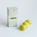 Three green olives with red stems next to a box labeled 'Pimento Olives' on a white background