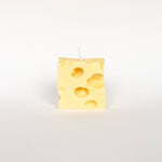 Rectangular yellow cheese-patterned candle on a white background