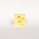 Rectangular yellow cheese-patterned candle on a white background