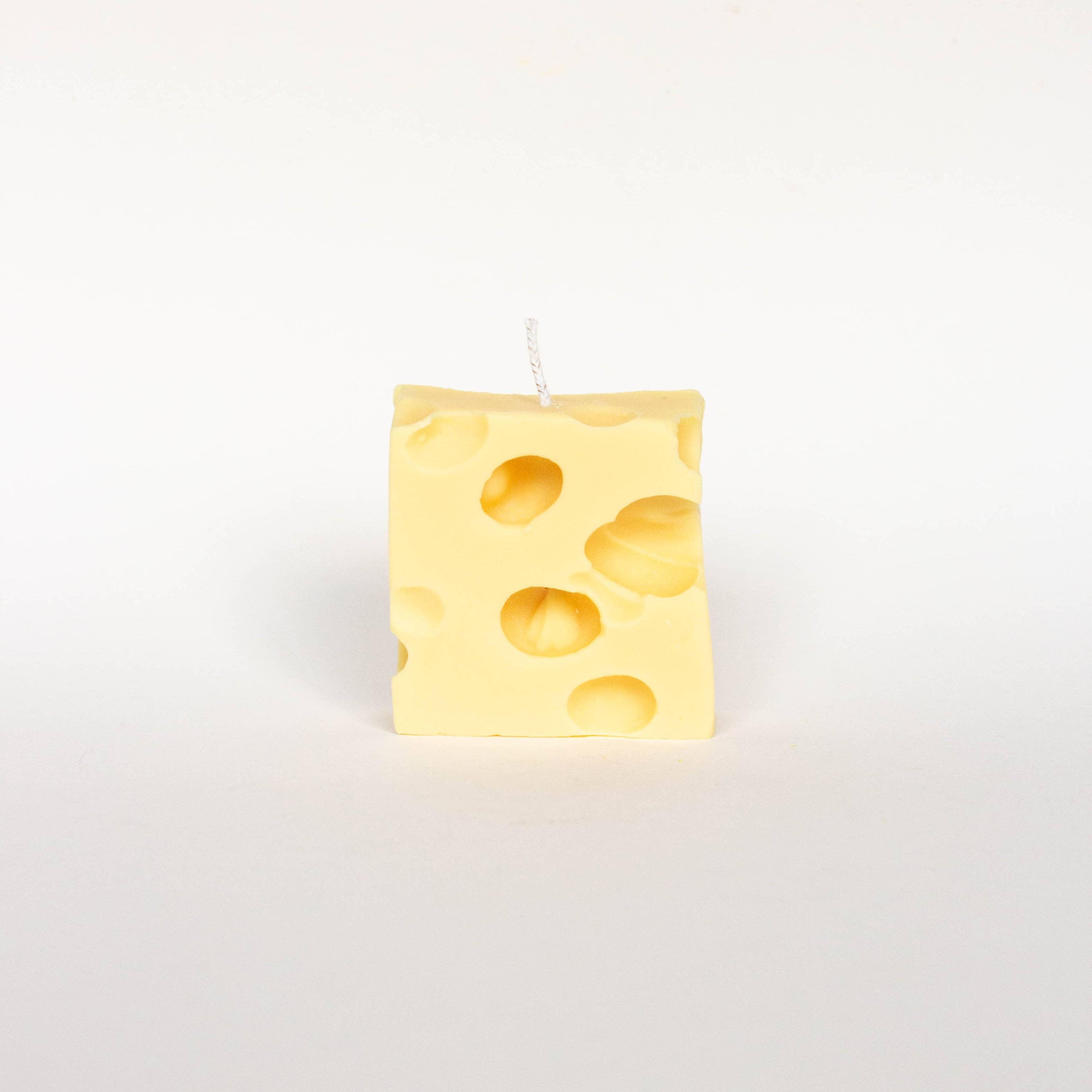 Rectangular yellow cheese-patterned candle on a white background