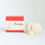 Burrata cheese-shaped candle with packaging on a white background