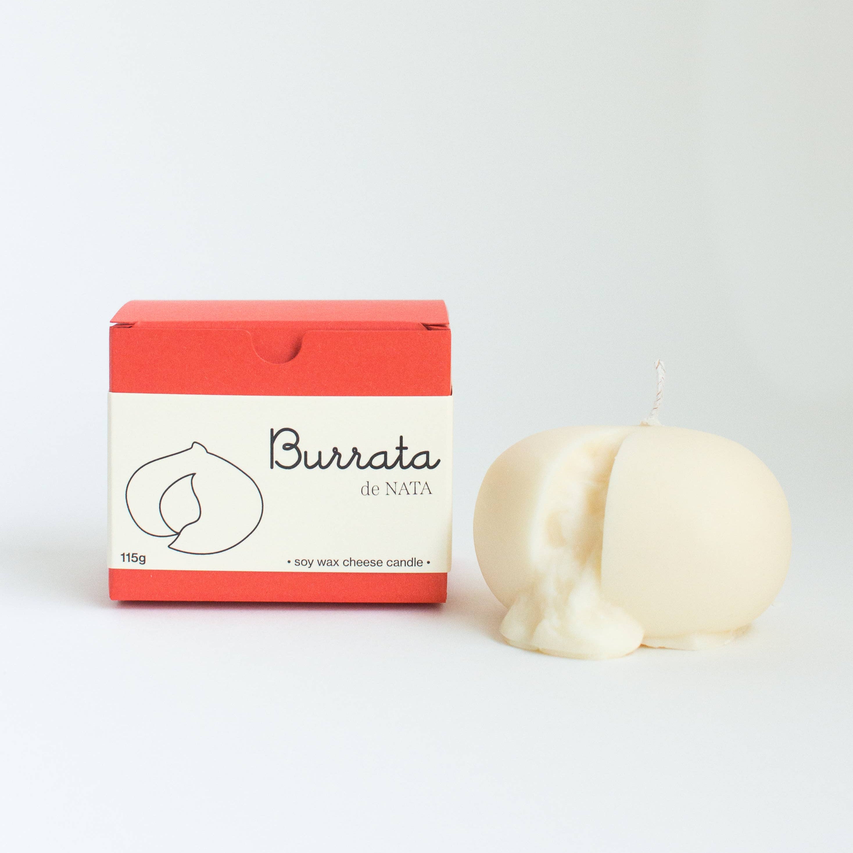 Burrata cheese-shaped candle with packaging on a white background