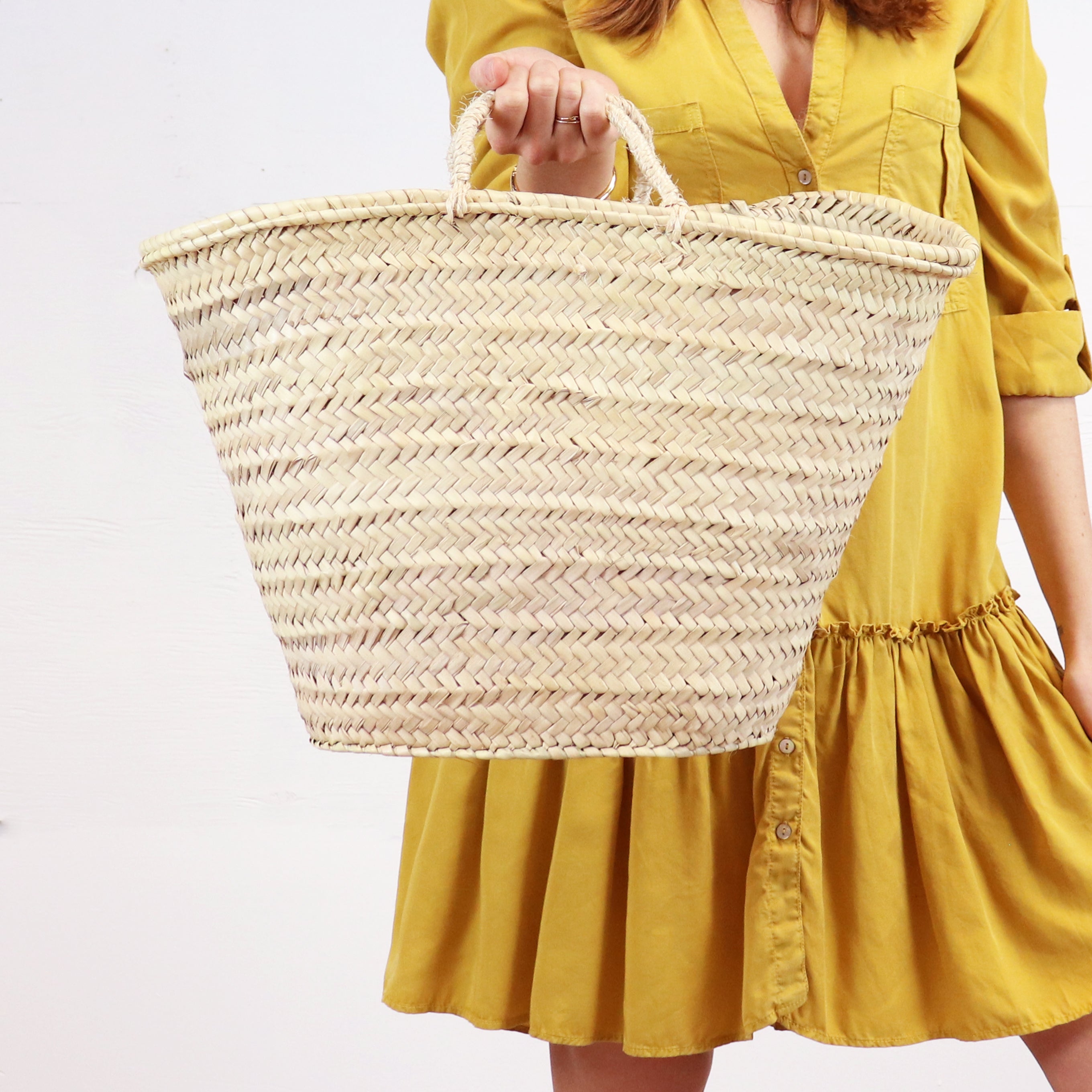 woman holding handwoven straw market basket with straps